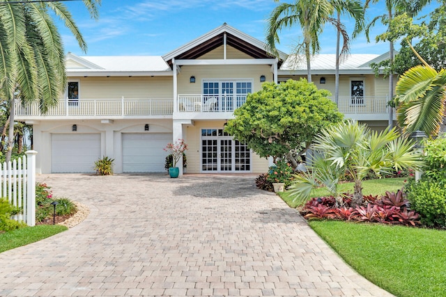 view of front of house featuring a garage, a balcony, and french doors