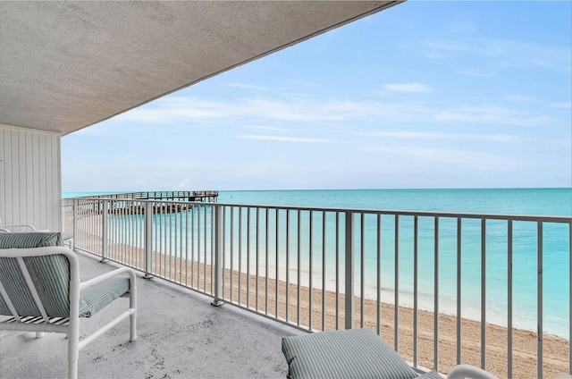 balcony featuring a beach view and a water view