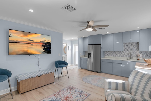 living room with crown molding, ceiling fan, sink, and light hardwood / wood-style floors