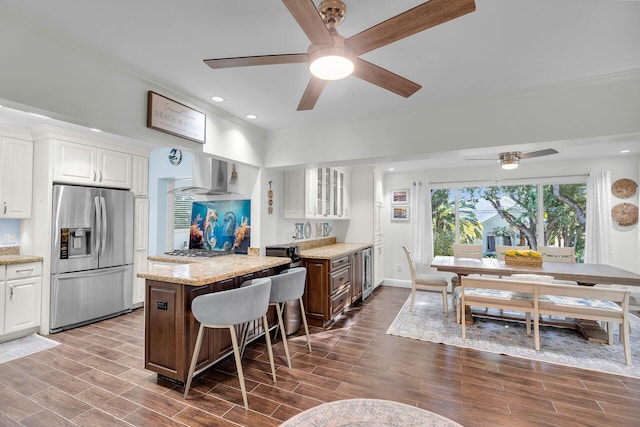 kitchen with a kitchen bar, white cabinetry, a center island, ventilation hood, and appliances with stainless steel finishes