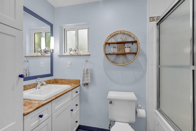 full bathroom featuring enclosed tub / shower combo, vanity, and toilet