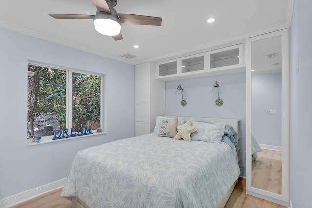 bedroom with ceiling fan, ornamental molding, and light hardwood / wood-style flooring