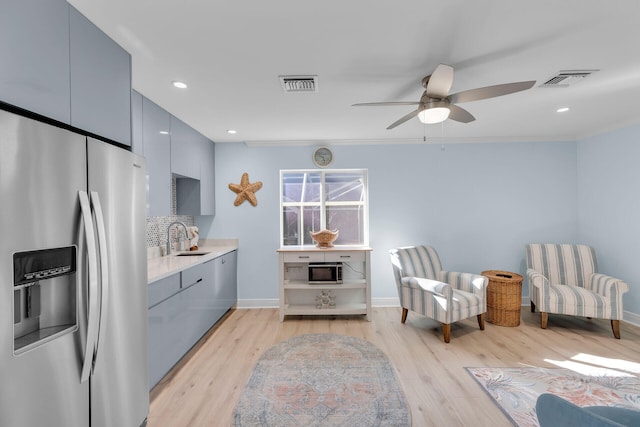 living area with sink, light hardwood / wood-style floors, and ceiling fan