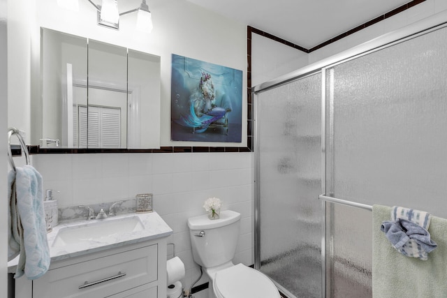 bathroom featuring a shower with door, vanity, tile walls, and toilet