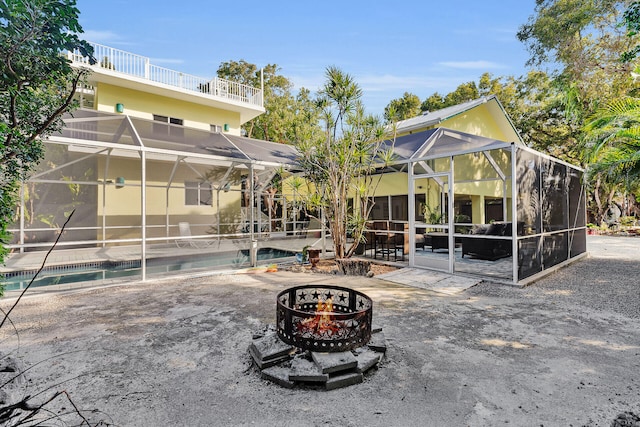 back of house featuring a patio, glass enclosure, and a fire pit