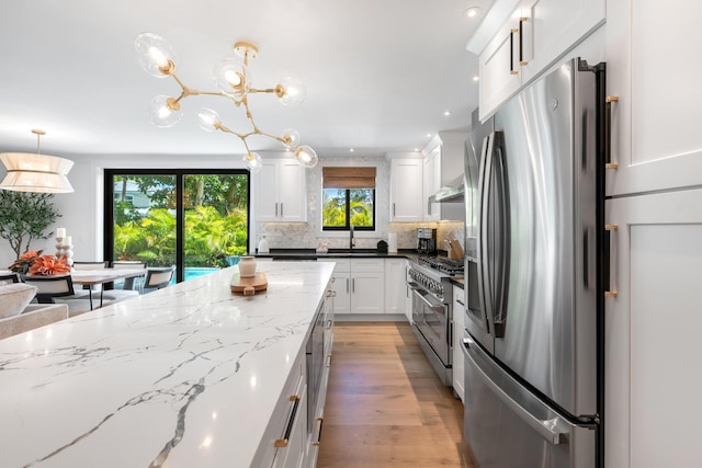 kitchen featuring white cabinetry, hanging light fixtures, dark stone countertops, stainless steel appliances, and tasteful backsplash