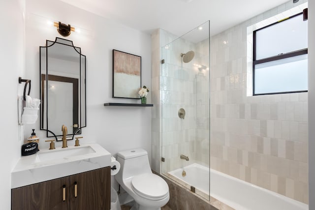 full bathroom featuring tiled shower / bath combo, vanity, and toilet