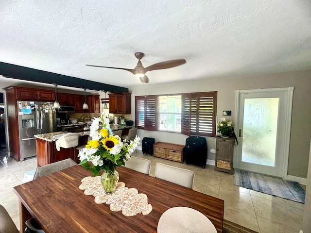 dining area featuring a textured ceiling, ceiling fan, and light tile patterned flooring