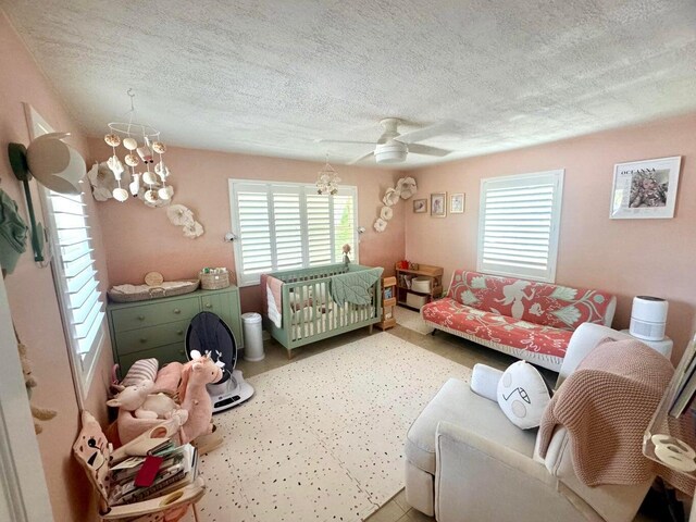 bedroom featuring ceiling fan with notable chandelier and a textured ceiling