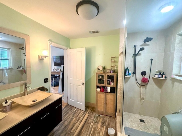 bathroom featuring hardwood / wood-style flooring, vanity, and tiled shower