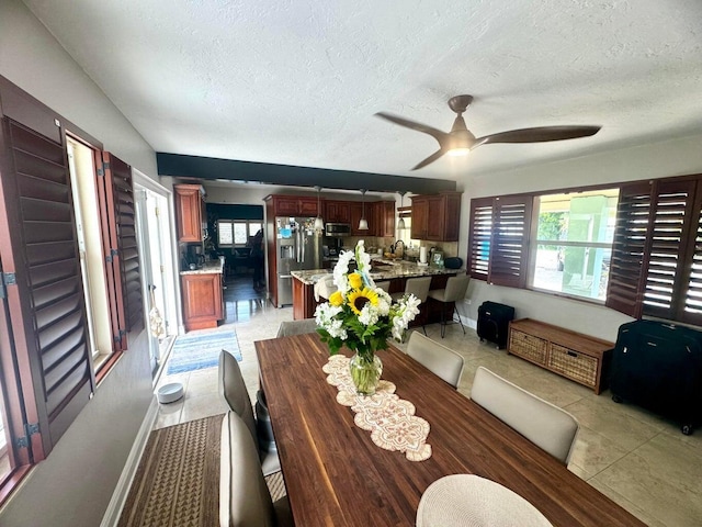 tiled dining room featuring sink, a textured ceiling, and ceiling fan