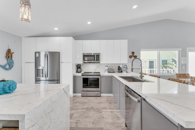 kitchen featuring appliances with stainless steel finishes, a sink, modern cabinets, and vaulted ceiling