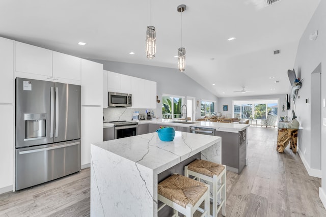 kitchen featuring a sink, light wood-type flooring, appliances with stainless steel finishes, and a peninsula