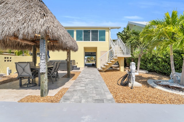 view of front facade with stairs, a patio, stucco siding, and outdoor dining area