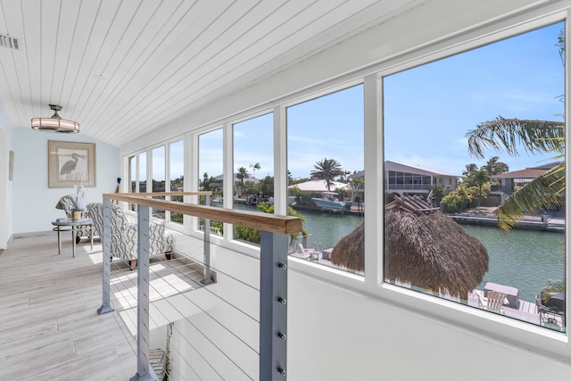 sunroom featuring wood ceiling, wood finished floors, and a water view