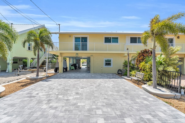 view of front of house featuring a carport, stairway, stucco siding, and decorative driveway