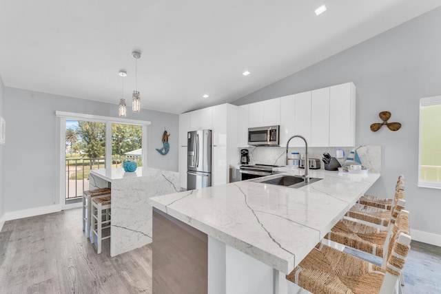 kitchen with vaulted ceiling, backsplash, a breakfast bar area, appliances with stainless steel finishes, and a sink