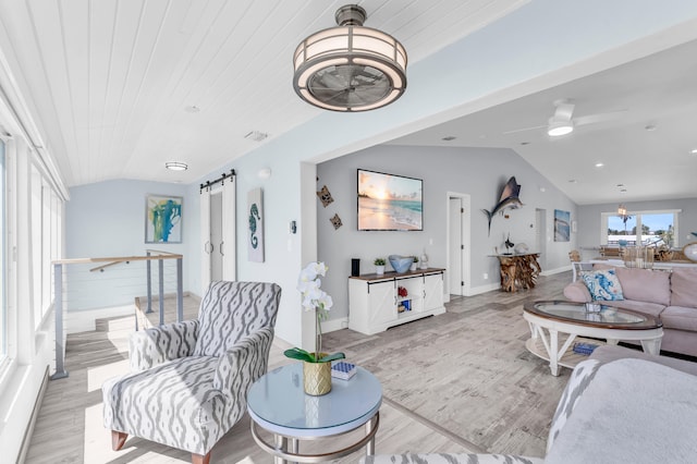 living room with wood finished floors, a ceiling fan, a barn door, and vaulted ceiling