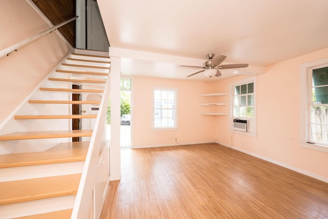 staircase featuring a ceiling fan, baseboards, and wood finished floors