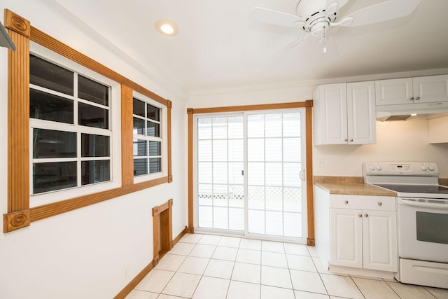 kitchen with white cabinets, white electric range oven, baseboards, light tile patterned floors, and under cabinet range hood
