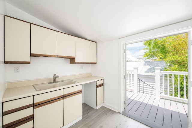 kitchen featuring a sink, light countertops, light wood-style flooring, white cabinetry, and baseboards