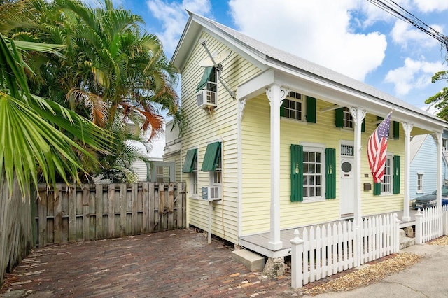 view of side of property featuring fence, covered porch, and cooling unit