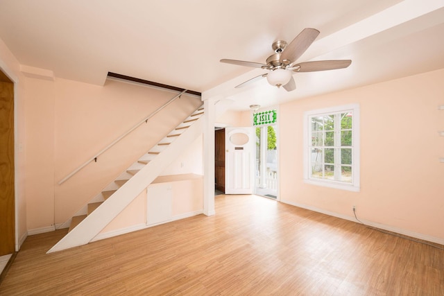 unfurnished living room featuring a ceiling fan, stairs, and wood finished floors