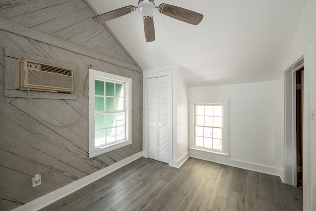 unfurnished bedroom with multiple windows, wood finished floors, baseboards, a closet, and lofted ceiling