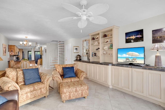 living area with light tile patterned floors, stairway, and ceiling fan with notable chandelier