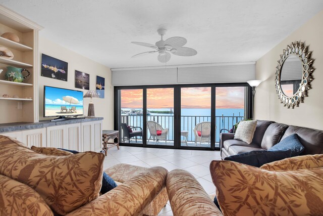 living area with a water view, a ceiling fan, and light tile patterned flooring