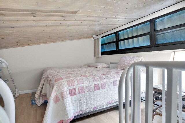 bedroom with lofted ceiling, light hardwood / wood-style floors, and wooden ceiling