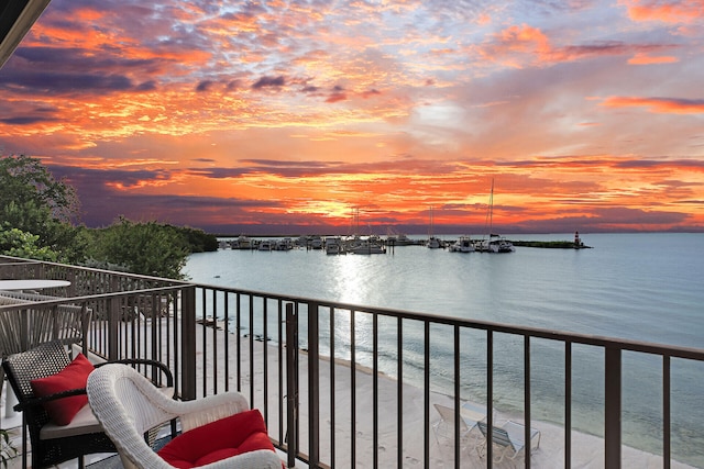 balcony at dusk featuring a water view