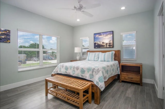 bedroom featuring ceiling fan, dark hardwood / wood-style floors, and multiple windows