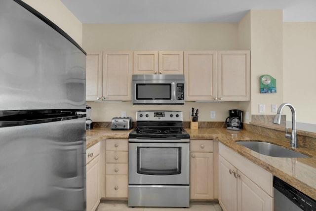 kitchen with light stone counters, stainless steel appliances, and a sink