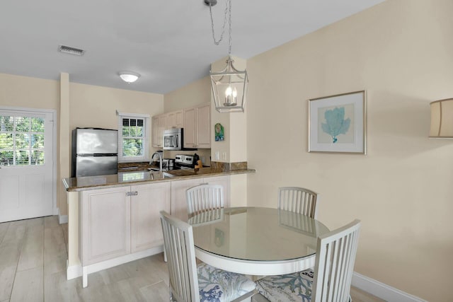 dining area featuring visible vents, a notable chandelier, light wood-style flooring, and baseboards