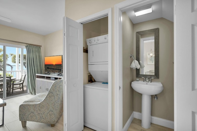 bathroom featuring a sink, baseboards, and stacked washer / dryer