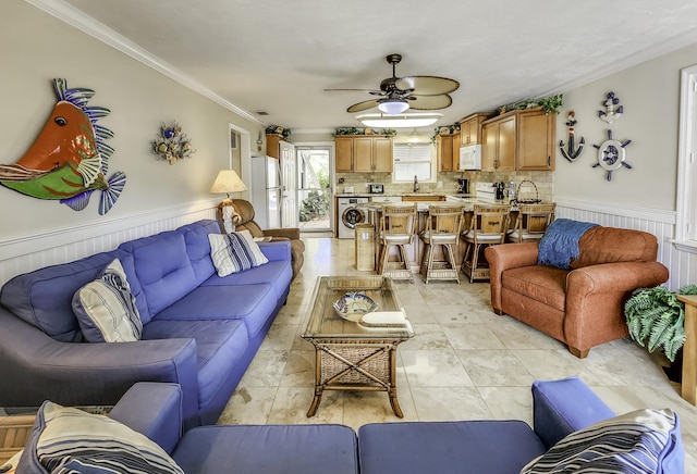 living room featuring washer / clothes dryer, ornamental molding, sink, and ceiling fan