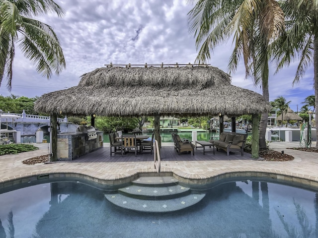 view of swimming pool featuring a grill, a gazebo, a patio, and exterior kitchen