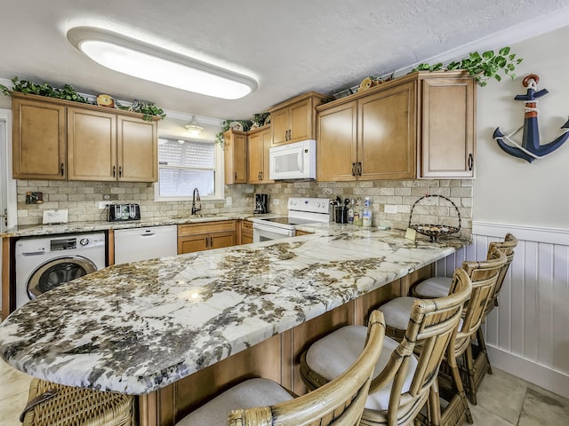 kitchen featuring washer / dryer, sink, backsplash, kitchen peninsula, and white appliances