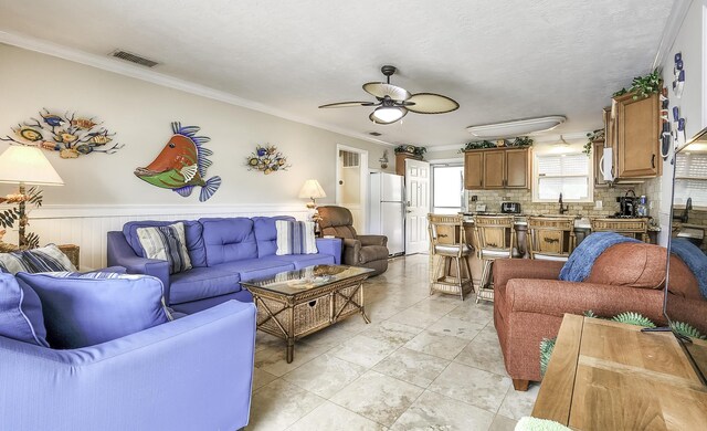 living room with crown molding, light tile patterned floors, a textured ceiling, and ceiling fan