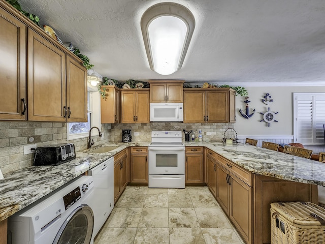 kitchen featuring washer / dryer, sink, a breakfast bar area, kitchen peninsula, and white appliances