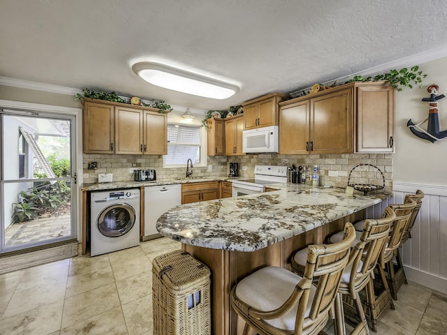 kitchen with washer / clothes dryer, sink, ornamental molding, kitchen peninsula, and white appliances