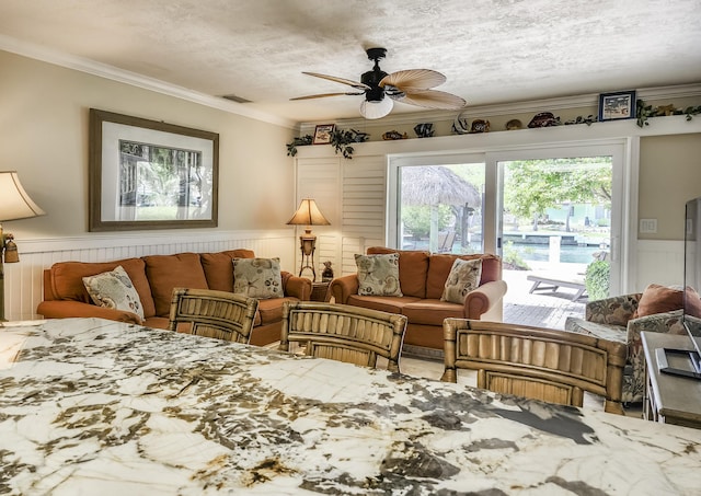 living room featuring ceiling fan, ornamental molding, and a textured ceiling