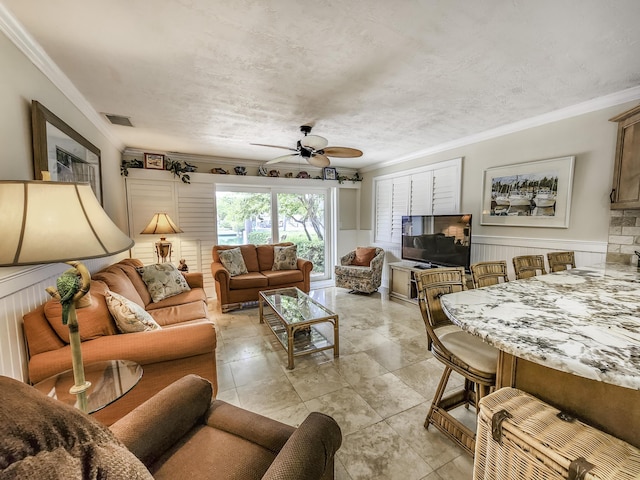 living room with crown molding, ceiling fan, and a textured ceiling