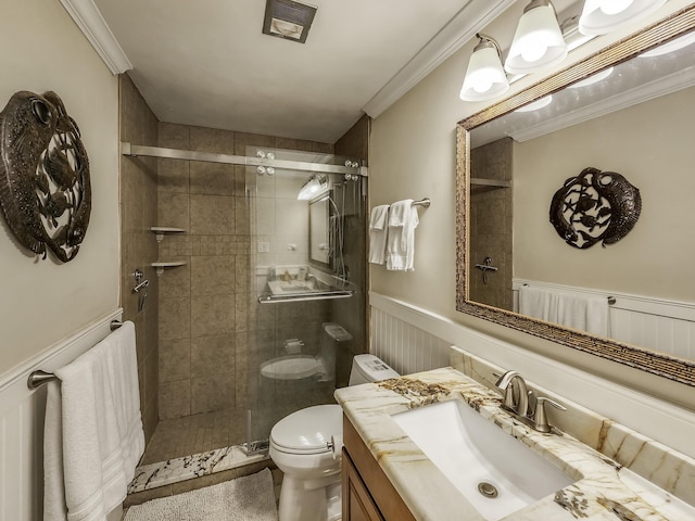 bathroom with ornamental molding, toilet, a shower with shower door, and vanity