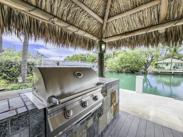 view of patio / terrace with exterior kitchen, a gazebo, a water view, and a grill