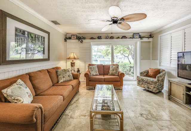 living room with ceiling fan, ornamental molding, and a textured ceiling