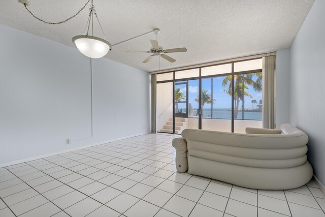 2000 Coco Plum Dr Unit 106, Marathon, FL 33050 - living area with a water view, ceiling fan, a wall of windows, a textured ceiling, and stairway