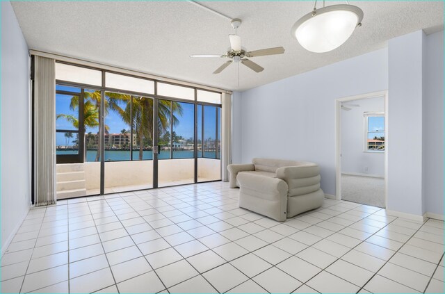 2000 Coco Plum Dr Unit 106, Marathon, FL 33050 - living area featuring a ceiling fan, a textured ceiling, a water view, and expansive windows