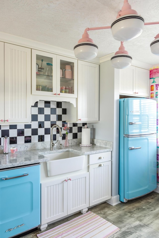 kitchen featuring refrigerator, tasteful backsplash, sink, white cabinets, and a textured ceiling